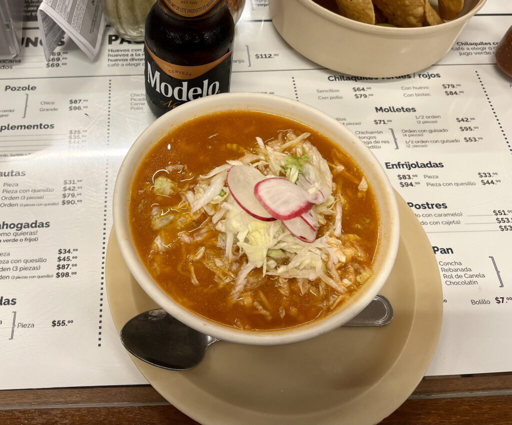 a bowl of pozole, an orange soup/stew with vegetables on top. Food from the Aztecs!