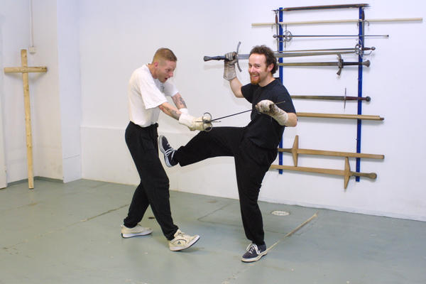 Guy pretending to kick Tomi in the nuts